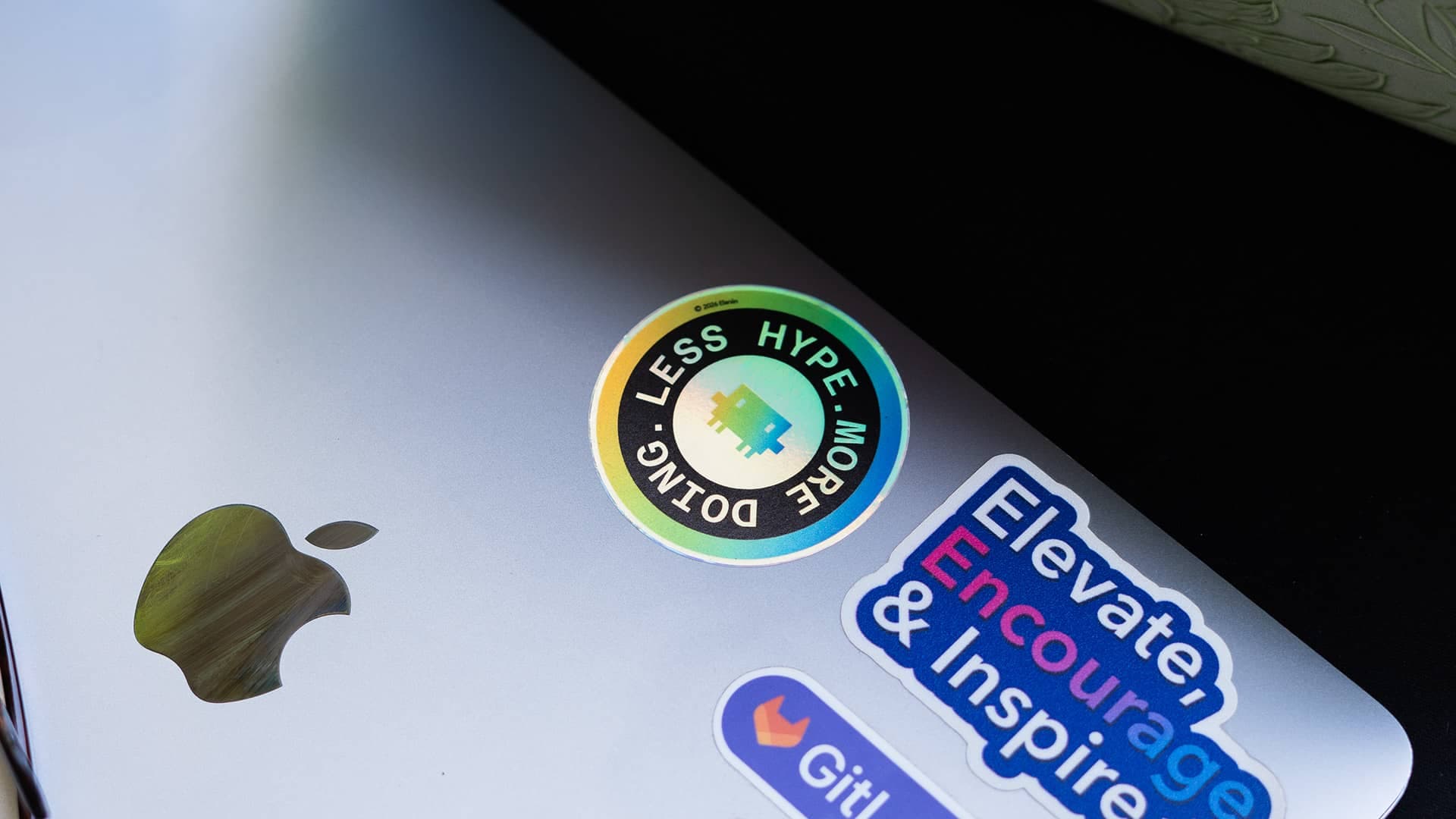 Holographic Less hype. More doing. sticker on a laptop