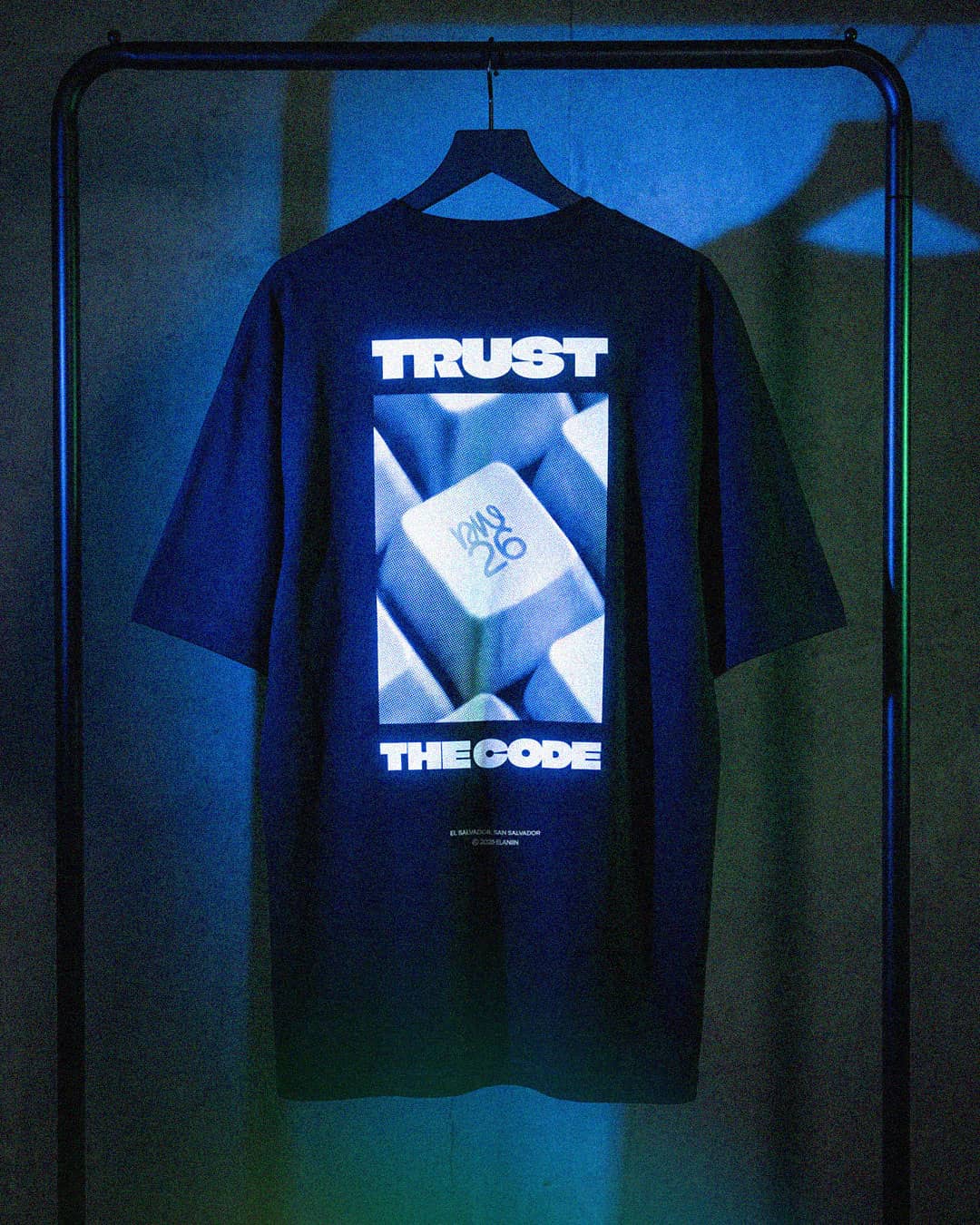 AI-generated Trust the Code tee hanging under blue light